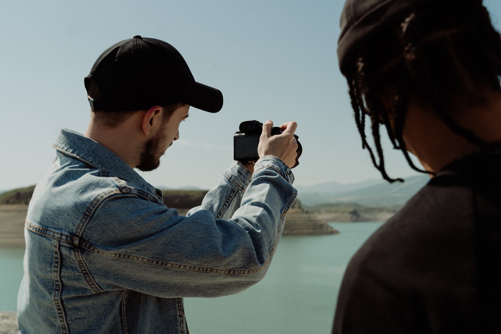 Man in Black Baseball Cap Taking a Photo Using Dslr Camera